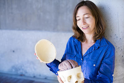 Portrait of SIlvia Bunge, UC Berkeley Psychology, holding a plastic skull with a model of a brain inside.
